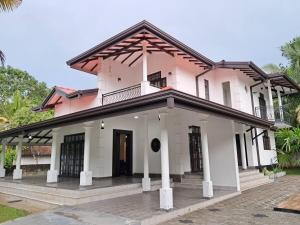 a pink house with a balcony on top of it at Tharan Villa - House in Colombo in Polgasowita