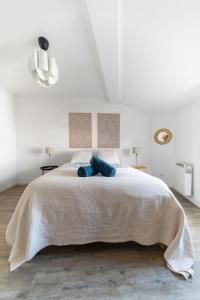 a white bedroom with a large bed with blue pillows at Grande Maison Clermont - Appartements centre ville in Clermont-Ferrand