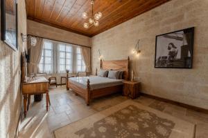 a bedroom with a bed and a desk in a room at Asmalı Konak Cave Suites of Cappadocia in Ürgüp