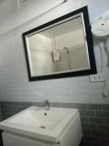 een badkamer met een witte wastafel en een spiegel bij Lamai Home 2 in Ko Yao Noi