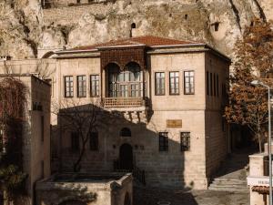an old stone building with a mountain in the background at Asmalı Konak Cave Suites of Cappadocia in Ürgüp