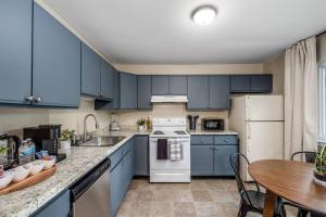 a kitchen with blue cabinets and a wooden table at Chic Remodeled Retreat Near EMU- Easy Commute apts in Ypsilanti