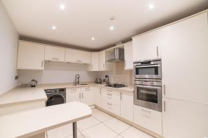 Una cocina blanca con gabinetes y electrodomésticos blancos. en The Kings Courtyard Apartment, en Bath