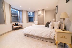 Un dormitorio con una cama y una silla y ventanas. en The Kings Courtyard Apartment, en Bath