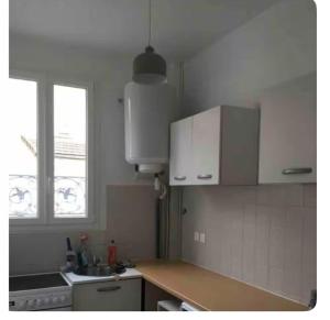 a kitchen with white cabinets and a sink and a window at Bon rapport qualité prix in Drancy