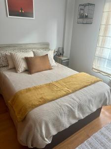 a bed with a yellow blanket on it in a bedroom at Piso centro A Coruña in A Coruña +6 photos