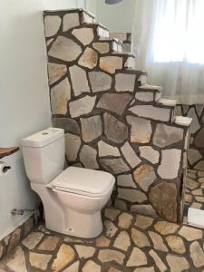 a bathroom with a toilet and a stone wall at Acacia Wilderness Mweya in Kasese