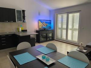 a kitchen with a dining table and a tv in it at Apartment Bumbar Sunset in Rogoznica