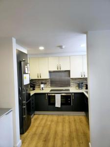 a kitchen with white cabinets and a black refrigerator at Luxury Hampstead Mews House, Close to City Centre in London