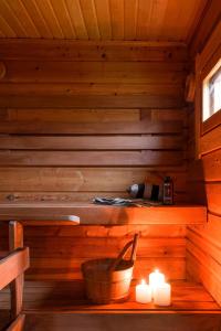 una sauna in legno con candele e una bottiglia di vino di Frosty Brook Cottage Hosted by Hygge Host a Lehtola Altre 34 foto