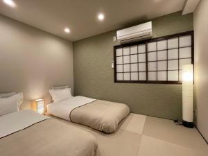 two beds in a room with a window and a window at 悦然民宿-天下茶屋 in Osaka