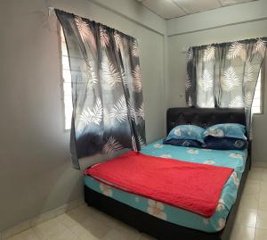 a small bedroom with a bed with a red blanket at Pakdin Homestay in Kampong Bukit Katil