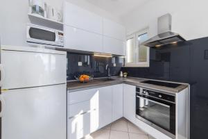eine Küche mit weißen Schränken und einem Herd mit Backofen in der Unterkunft Apartment Tafra 2 in Lokva Rogoznica
