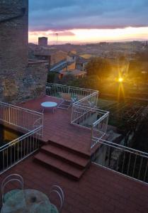un balcón con escaleras, una mesa y una puesta de sol en Appartamento Le Palme con terrazze in centro, en San Gimignano