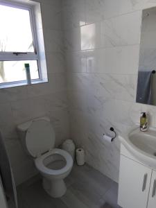 a white bathroom with a toilet and a sink at Marina Cottage in Marina Da Gama +8 photos