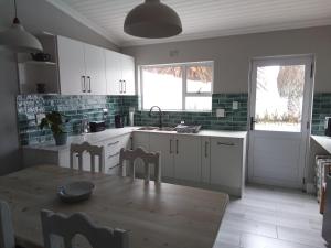 a kitchen with white cabinets and a table and a sink at Marina Cottage in Marina Da Gama
