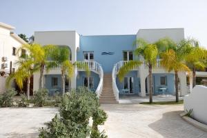 a blue building with palm trees in front of it at Le Onde della Sicciara in Balestrate