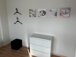 a white room with a dresser and a wall with pictures at Fewo-H41 in Korschenbroich