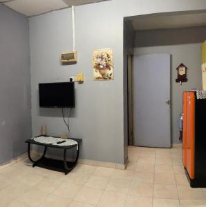 a room with a tv and a table and a door at Pakdin Homestay in Kampong Bukit Katil