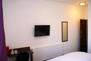 een slaapkamer met een tv aan de muur en een bed bij The Hindes Hotel in Harrow