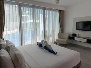 a hotel room with a white bed with a television at Direct pool access studio Twin Sands by Lofty in Patong Beach