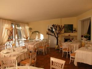 comedor con mesas y sillas blancas y chimenea en Hotel Olympic, en Saint Vincent