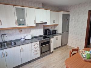 a kitchen with white cabinets and a wooden table at Apartamento Noa in Muxia
