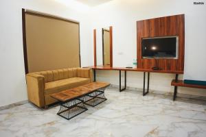 a waiting room with a couch and a tv at The Krati Resort & Convention Centre in Bareilly