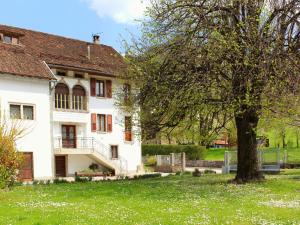 a large white house with a tree in the yard at Albergo Diffuso Comeglians in Comeglians