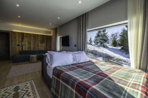 a bedroom with a bed and a large window at Chalet 1600 Kopaonik & Spa in Kopaonik