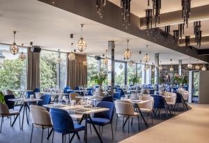 a dining room with tables and chairs and large windows at Grand Hotel Adriatic in Opatija