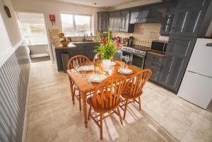 a kitchen with a wooden table with chairs and a refrigerator at 10 Cuddy Point, Scalpay in Scalpay