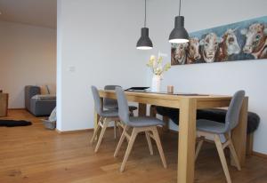 a dining room table with four chairs and a painting of dogs at Daslichtenberg Eastside in Saalfelden am Steinernen Meer