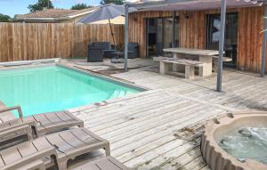 a pool with a wooden deck with a picnic table and an umbrella at Beautiful Home In Ares in Arès