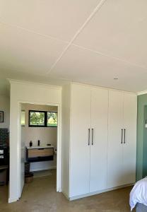 a bedroom with white cabinets and a desk at Stylish Cottage on secure estate in Howick +6 photos