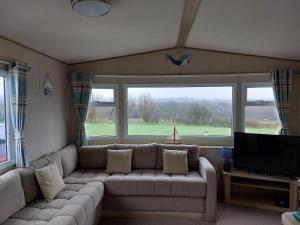 Una sala de estar con un sofá y un televisor de pantalla plana. en Gateway to Cornwall, en St Austell