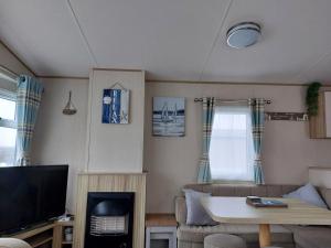 Una sala de estar con un sofá y un televisor. en Gateway to Cornwall, en St Austell