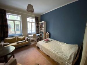 una camera da letto con pareti blu, un letto e un divano di Gemütliches Zimmer im Zentrum Weimars a Weimar