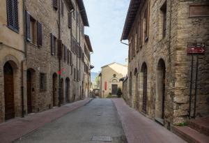 un callejón vacío entre dos edificios de ladrillo en Appartamento Le Palme con terrazze in centro, en San Gimignano