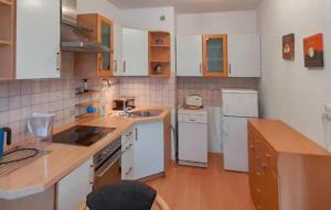 a small kitchen with white appliances and wooden floors at Nice Apartment In Pobierowo With Wifi in Pobierowo