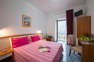 una camera da letto con un letto rosa con un libro sopra di Dint'a Torre Bed and Breakfast a Scala
