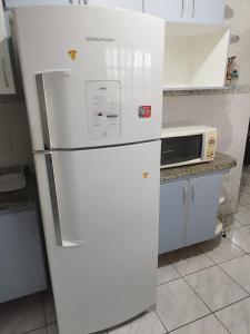 Un refrigerador blanco en una cocina con microondas. en BONA CASA PERUÍBE, en Peruíbe