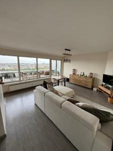 a living room with a white couch and a large window at Air Bey Penthouse in Brussels