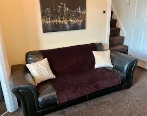 a brown leather couch in a living room with a staircase at Central Halifax Work & Retreat Base - Two bedroom house - sleeps up to 4 - free parking and internet in Halifax