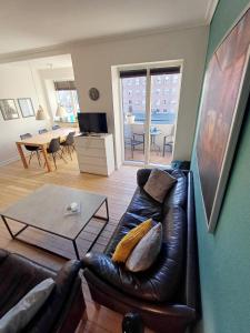 a living room with a leather couch and a table at Beautiful 3 bedroom apartment in Central City in Aalborg