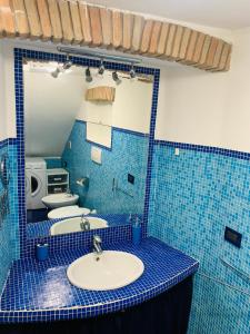 a blue tiled bathroom with a sink and two toilets at L'Archetto Apartment in Rieti