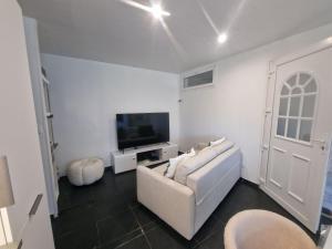 a white living room with a white couch and a tv at Appartement a 2 pas de la plage in Rogliano