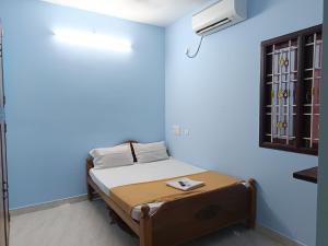 a bed in a room with a blue wall at Seasons4 Homestay in Virāmpattinam