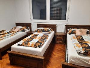 three beds in a room with a window at Farkas Szállás in Báránd +7 photos