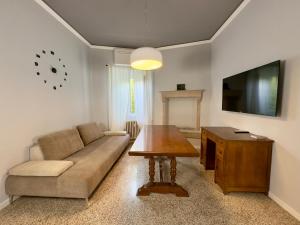 a living room with a couch and a table and a tv at Casa di Romeo - Valpolicella in Negrar